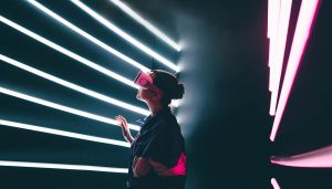 Girl using VR goggles in colorful neon lights.