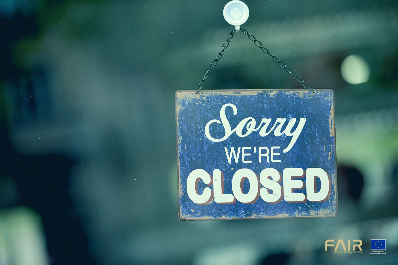 Close-up on a blue closed sign in the window of a shop displaying the message "Sorry we are closed"