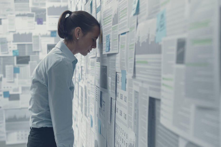 Exhausted depressed businesswoman leaning on a wall covered with financial charts and feeling hopeless, business failure concept