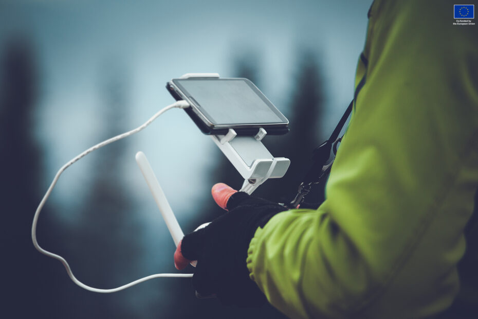 Man in green jacket operating a drone using a remote controller. Winter holidays in mountains. Close up picture. Bukovel, Carpathians, Ukraine, Europe. Exploring beauty world